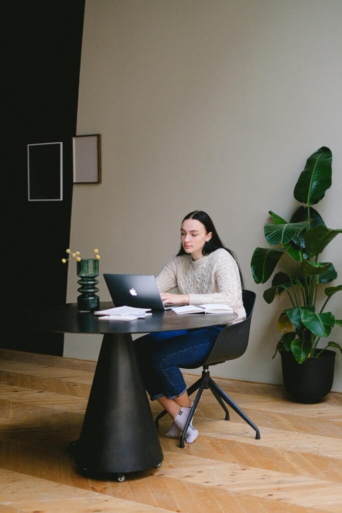 A young woman working on a laptop in a stylish and modern home office with indoor plants.